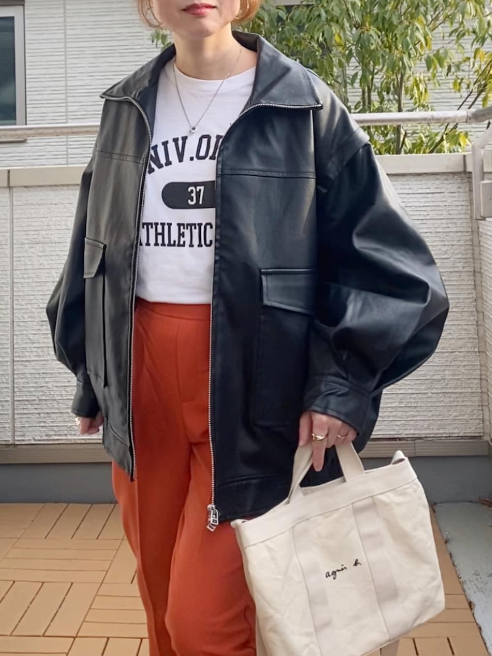ブラック系のライダースジャケット、ホワイト系のTシャツ/カットソー、オレンジ系のその他パンツを着用したレディースの冬コーディネートの4枚目の写真