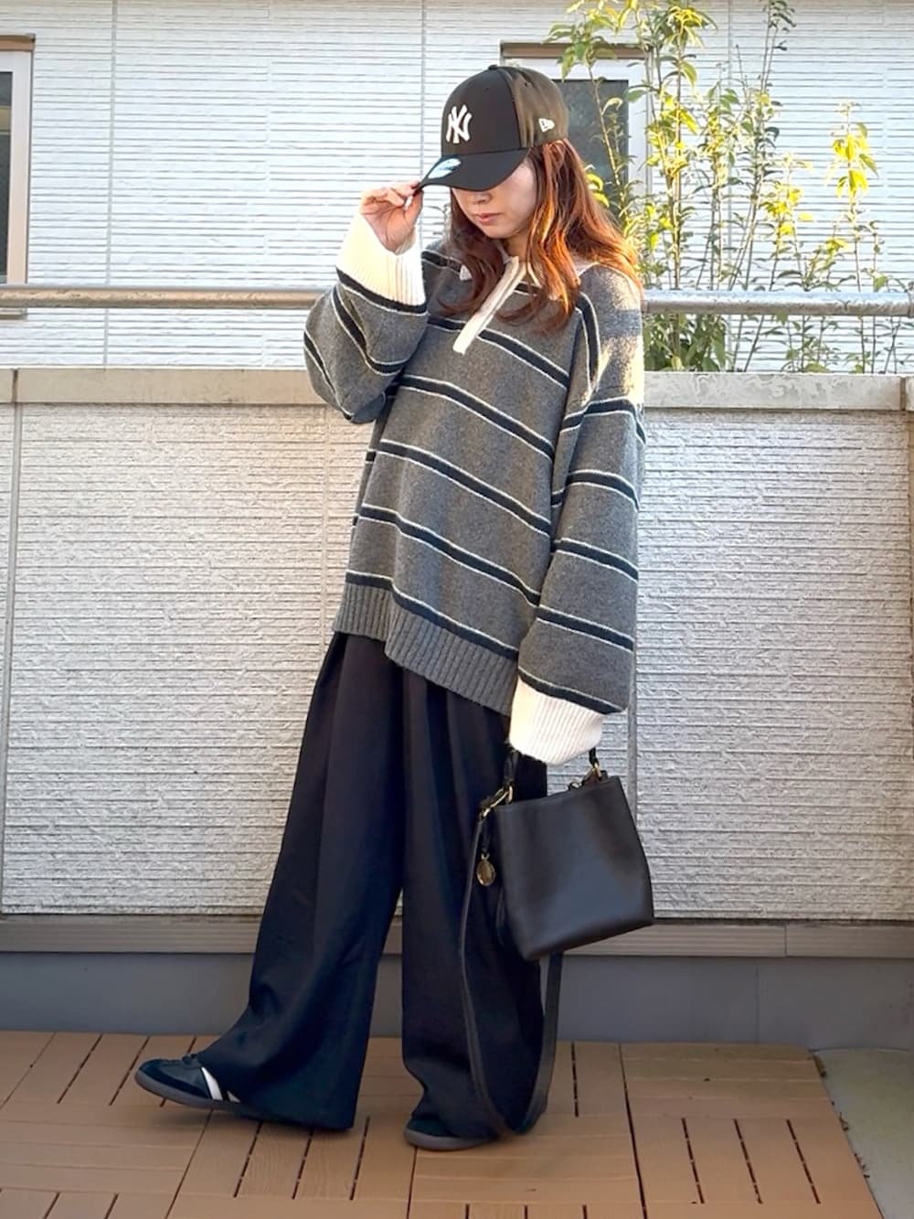 グレー系のニット/セーター、ブラック系のショルダーバッグ、ブラック系のスラックスを着用したレディースの冬コーディネートの2枚目の写真