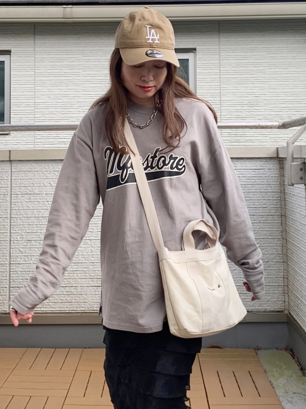 グレー系のTシャツ/カットソー、ブラック系のスカート、ホワイト系のトートバッグを着用したレディースの春コーディネートの4枚目の写真