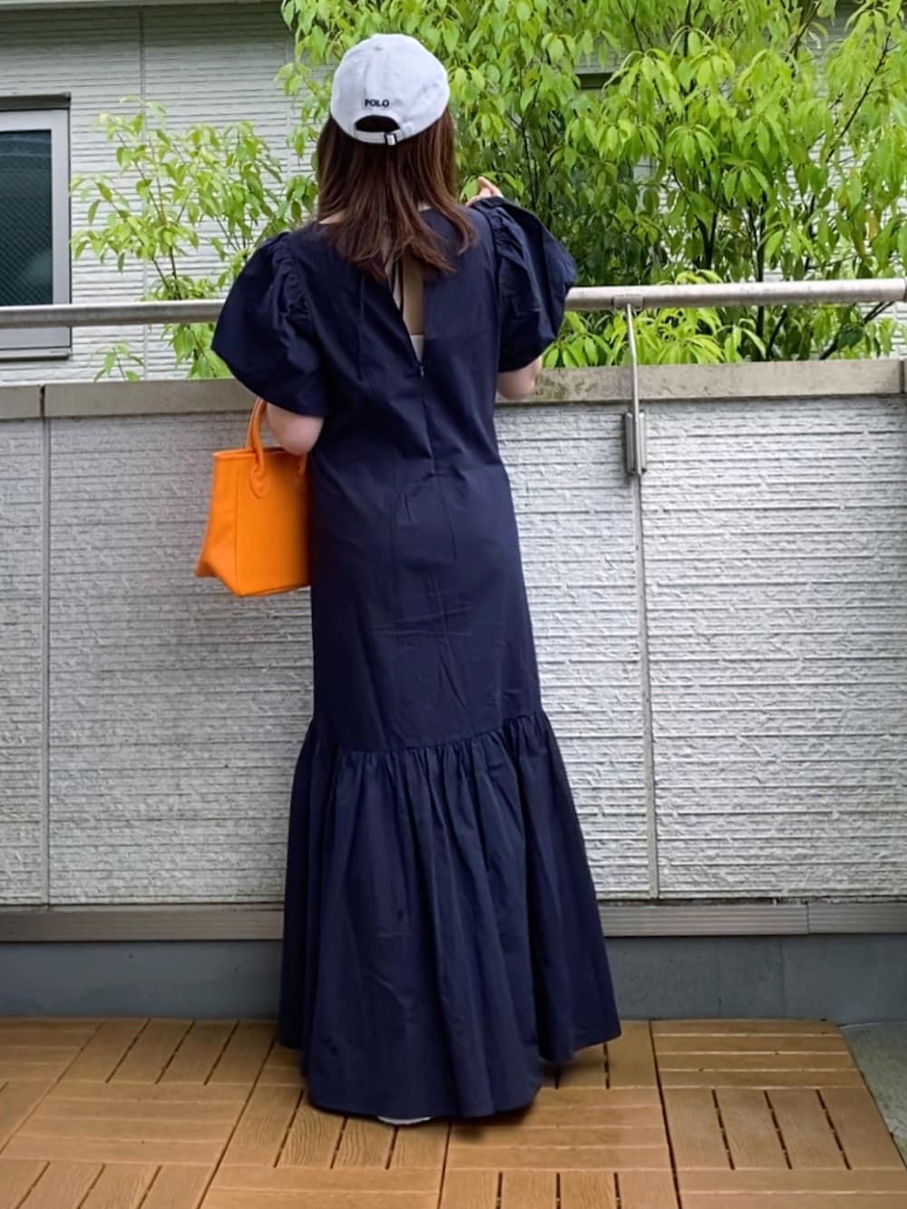 ブルー系のワンピース、オレンジ系のトートバッグ、ホワイト系のサンダルを着用したレディースの春コーディネートの2枚目の写真