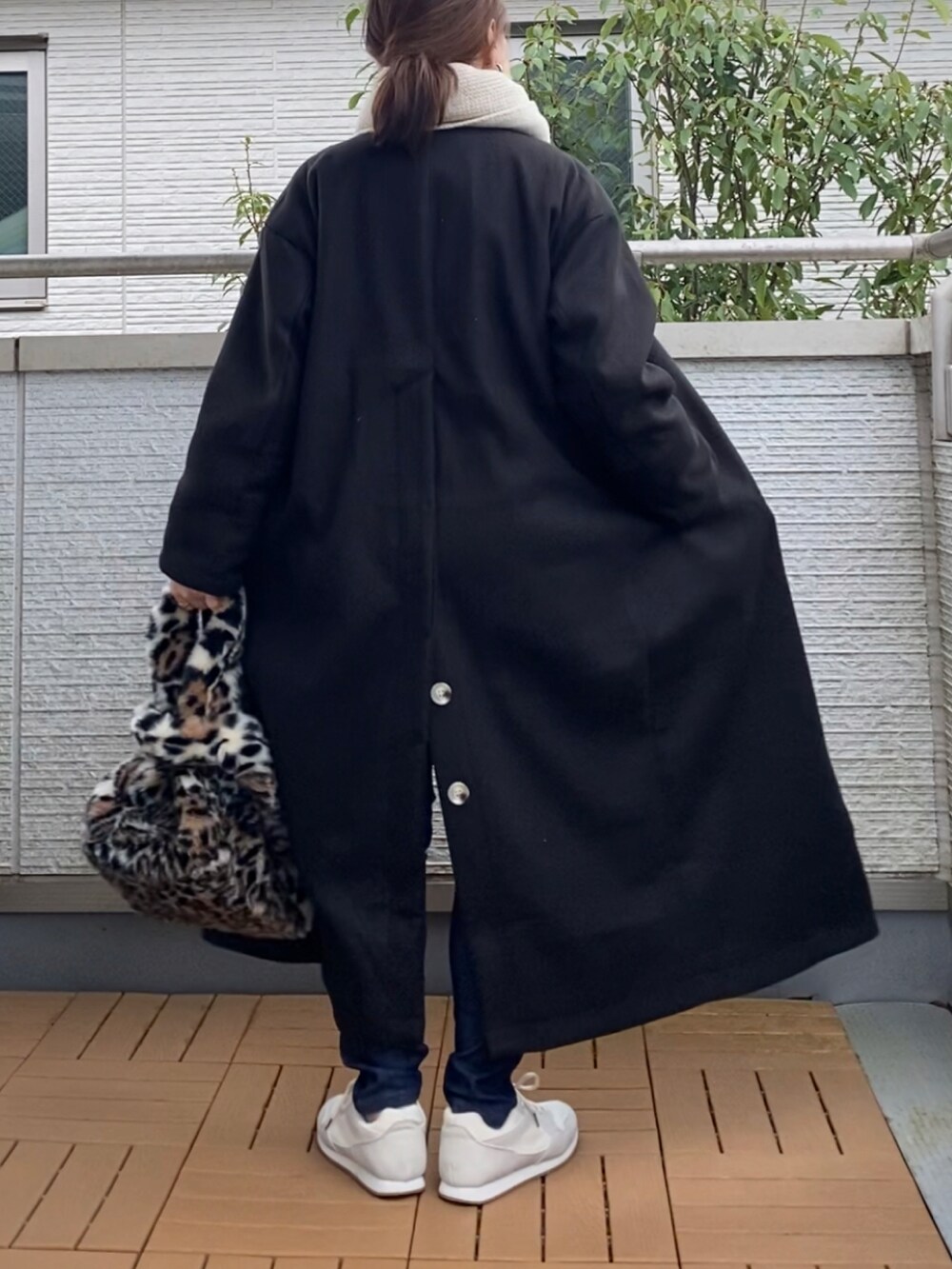 ブラック系のノーカラーコート、ホワイト系のニット/セーター、ブルー系のデニムパンツを着用したレディースの秋コーディネートの3枚目の写真