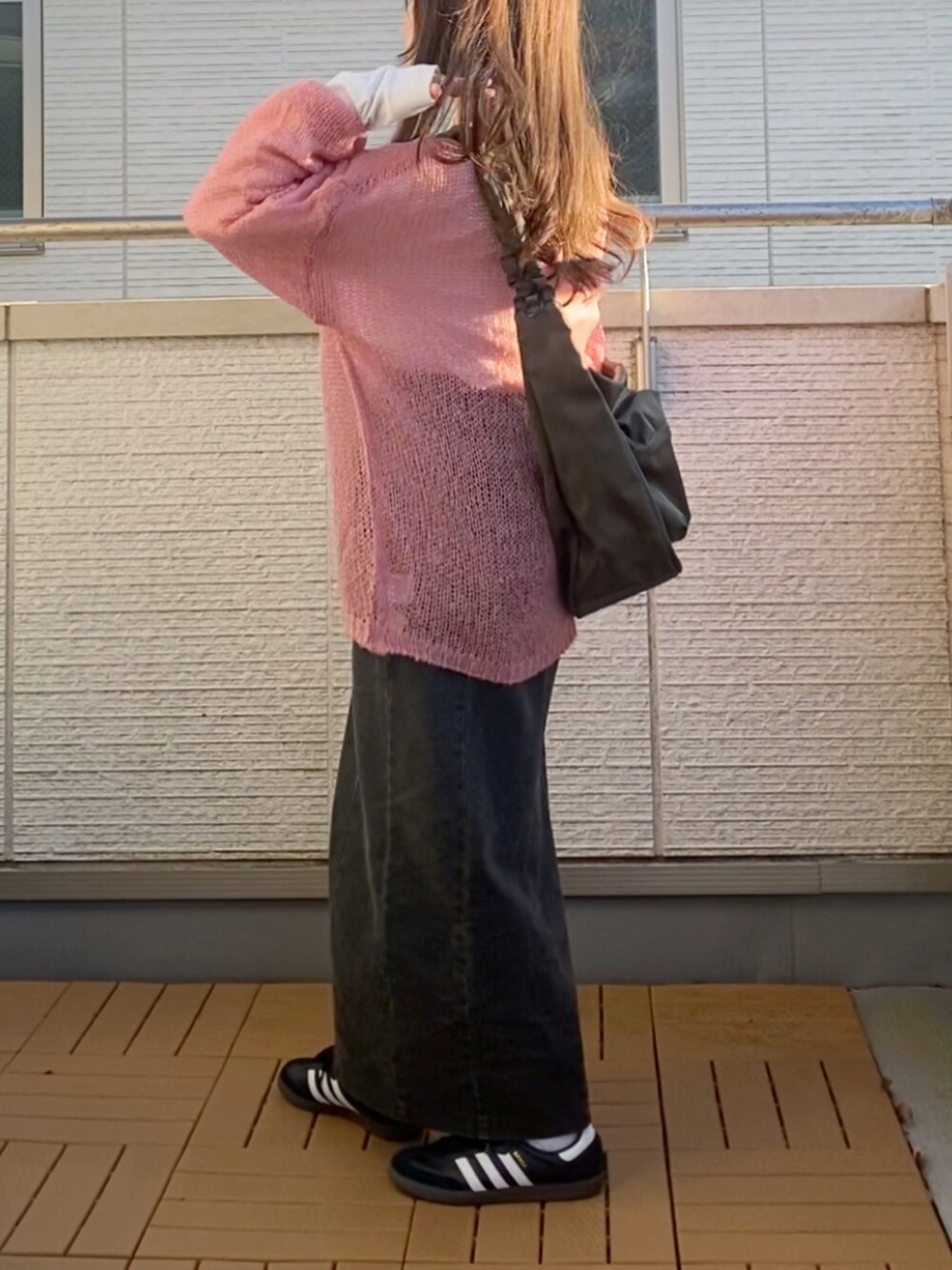 ピンク系のニット/セーター、ブラック系のスカート、グリーン系のショルダーバッグを着用したレディースの冬コーディネートの3枚目の写真