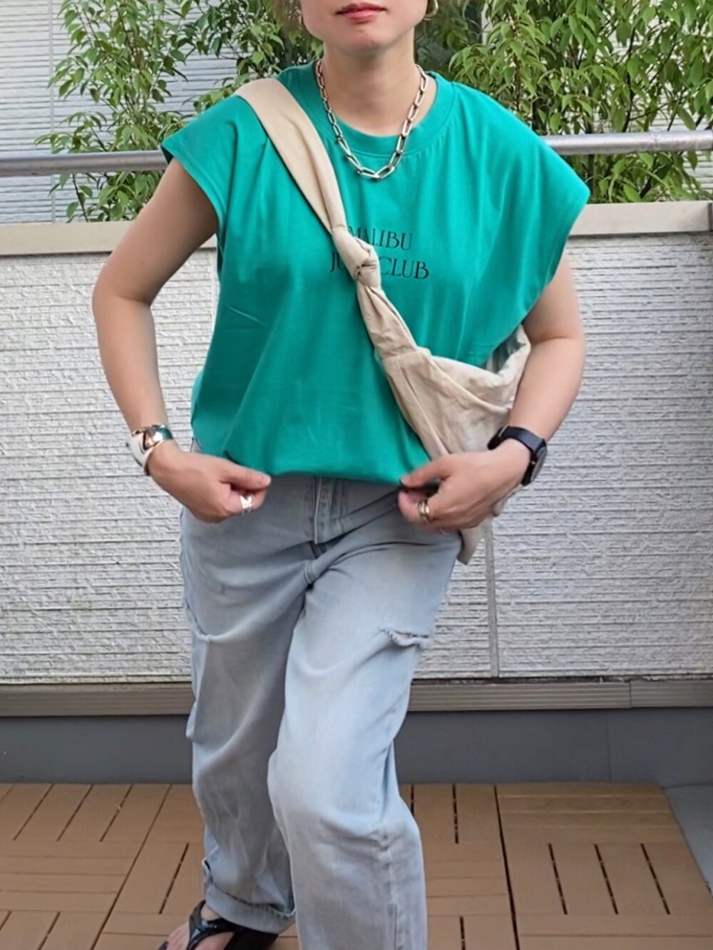 グリーン系のTシャツ/カットソー、ブルー系のデニムパンツ、ホワイト系のショルダーバッグを着用したレディースの夏コーディネートの4枚目の写真