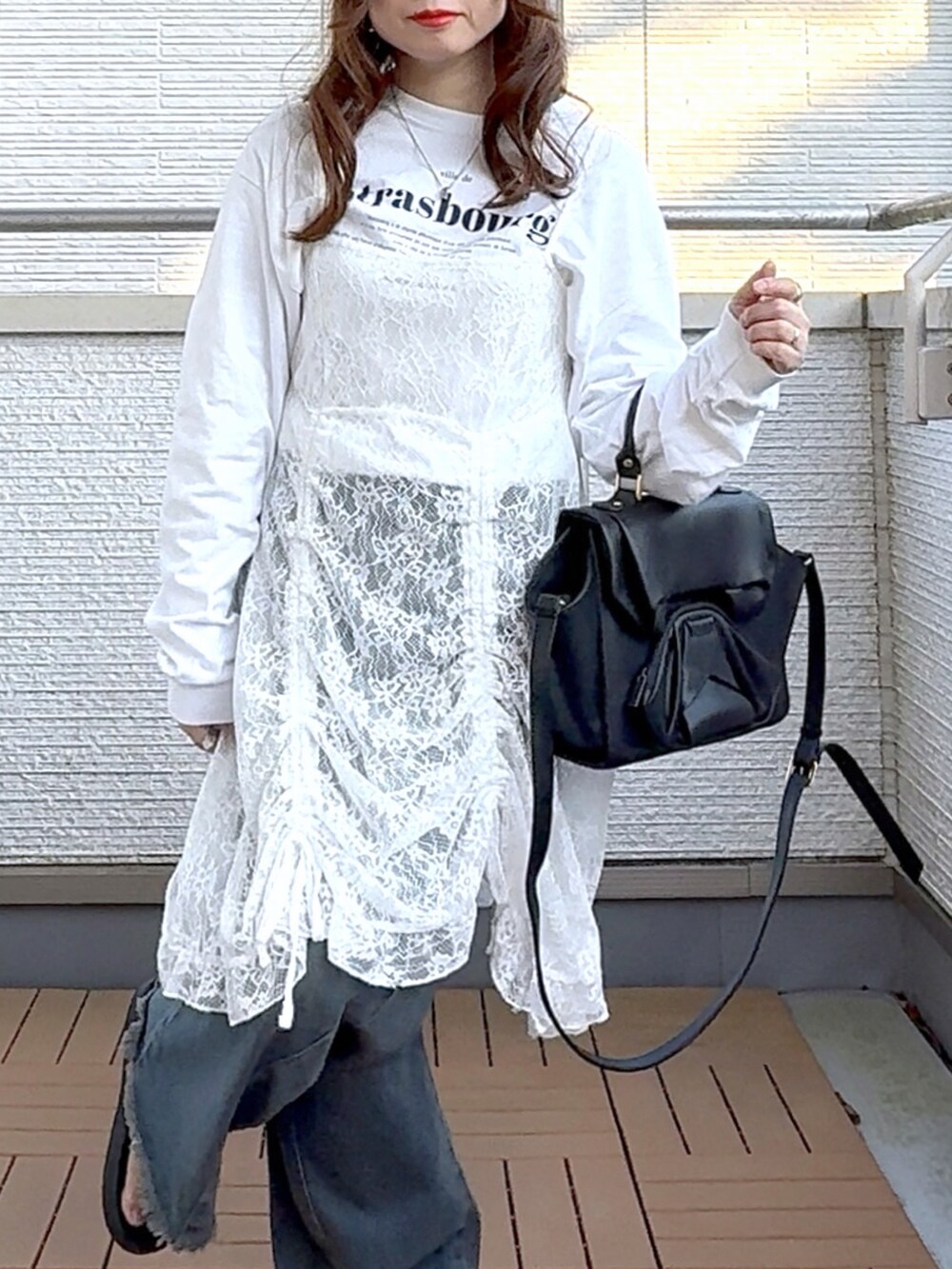 ホワイト系のワンピース、ブルー系のデニムパンツ、ブラック系のハンドバッグを着用したレディースの春コーディネートの5枚目の写真