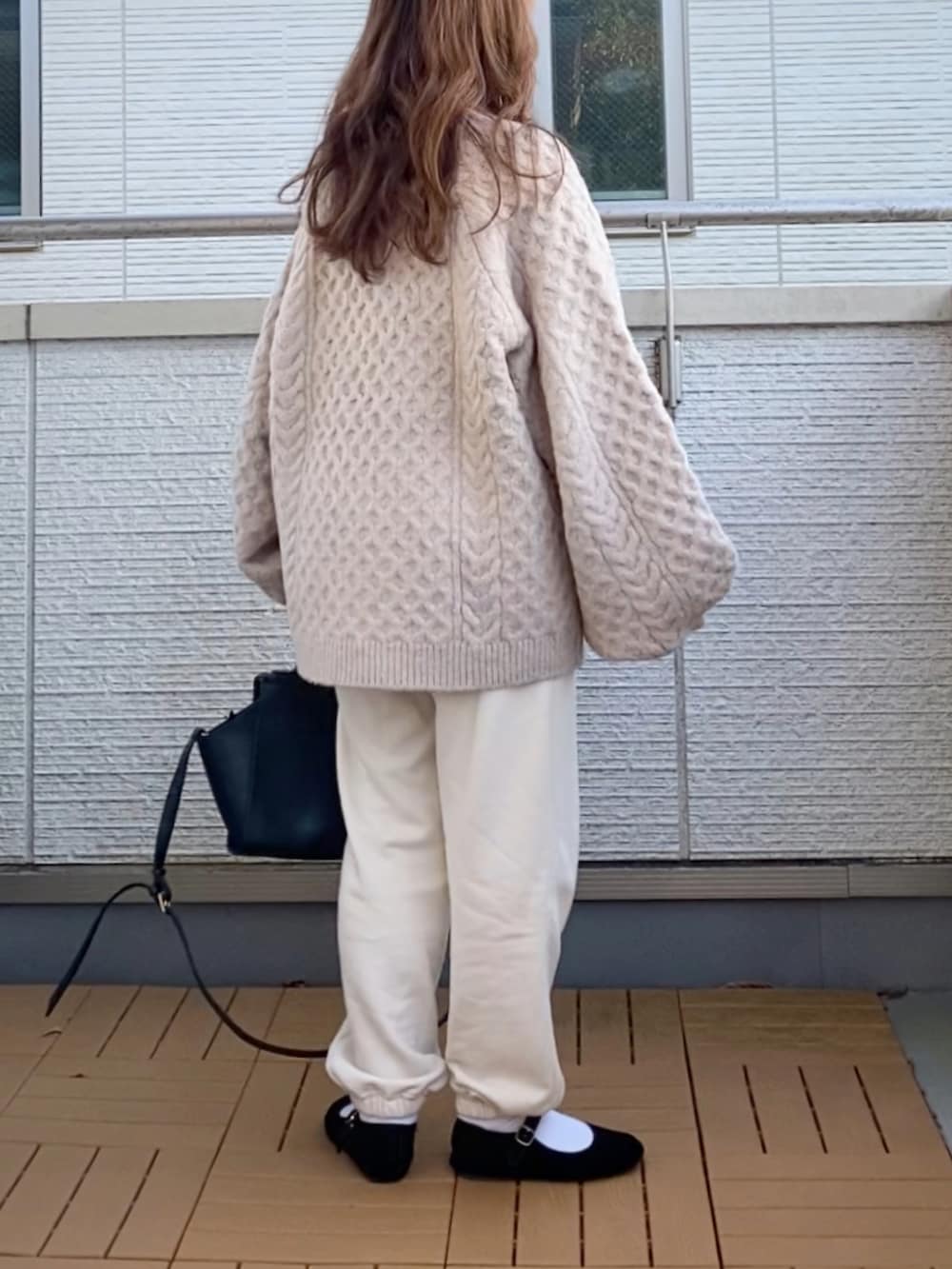 ベージュ系のニット/セーター、ホワイト系のパンツ、ブラック系のハンドバッグを着用したレディースの秋コーディネートの4枚目の写真