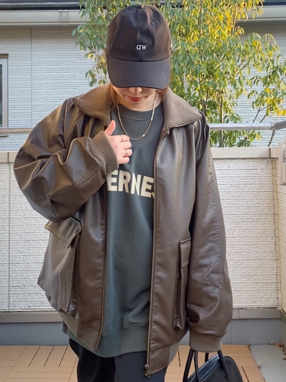 ブラウン系のライダースジャケット、グリーン系のスウェット、ブラック系のその他パンツを着用したレディースの冬コーディネートの3枚目の写真