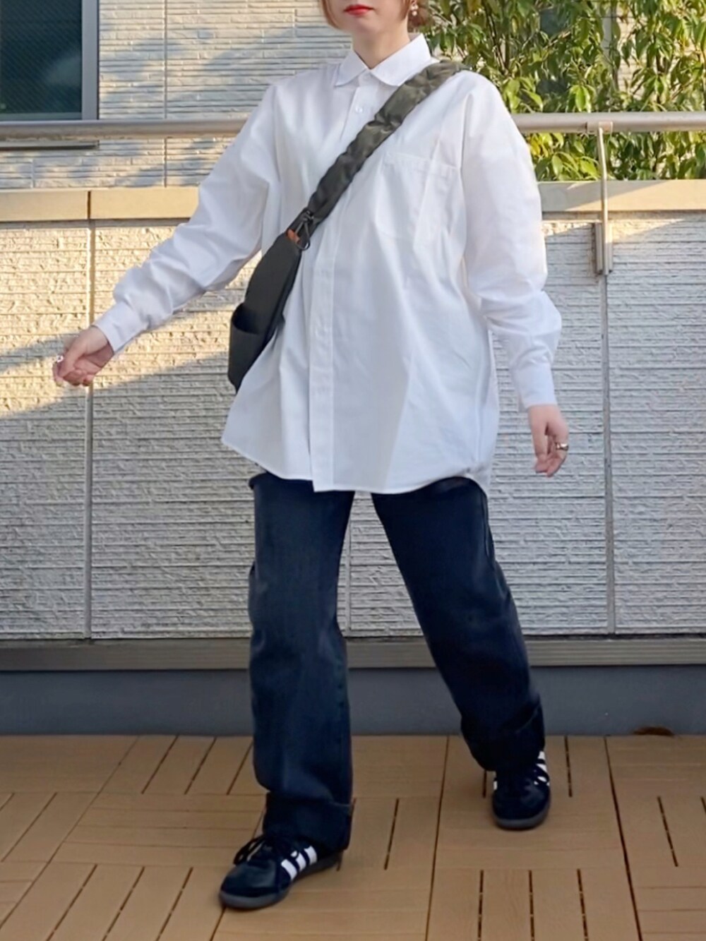 ホワイト系のシャツ/ブラウス、ブラック系のデニムパンツ、グリーン系のショルダーバッグを着用したレディースの春コーディネートの2枚目の写真