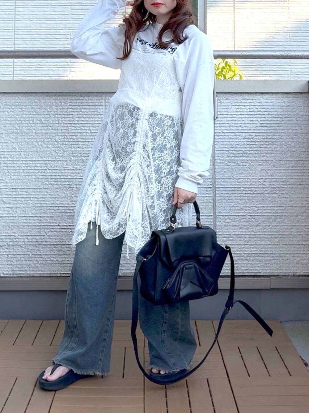 ホワイト系のワンピース、ブルー系のデニムパンツ、ブラック系のハンドバッグを着用したレディースの春コーディネートの2枚目の写真