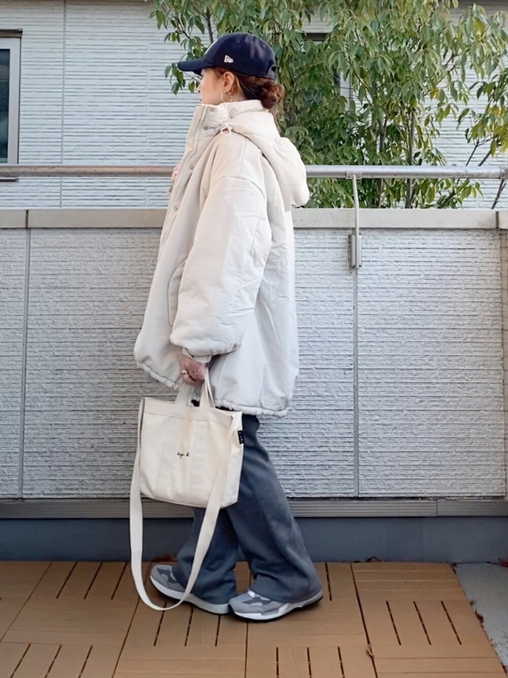 ホワイト系のダウンジャケット/コート、グレー系のカーディガン/ボレロ、グレー系のスラックスを着用したレディースの冬コーディネートの2枚目の写真