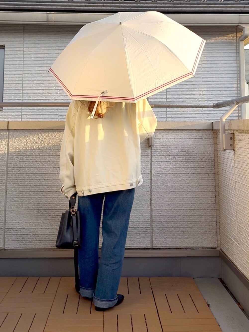 ホワイト系のデニムジャケット、ブルー系のデニムパンツ、ブラック系のショルダーバッグを着用したレディースの春コーディネートの3枚目の写真