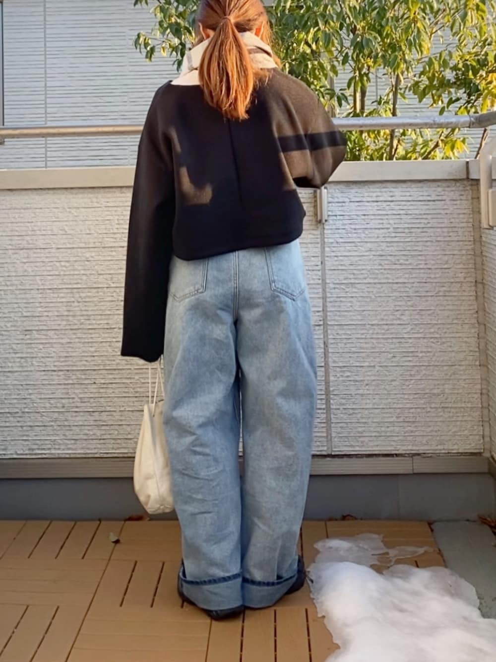 ブラック系のワンピース、ブルー系のデニムパンツ、ブラック系のスニーカーを着用したレディースの冬コーディネートの3枚目の写真