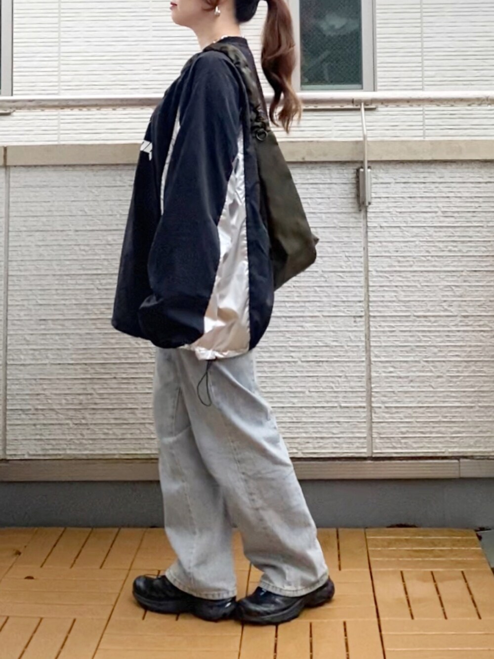 ブラック系のトップス、ブルー系のデニムパンツ、グリーン系のショルダーバッグを着用したレディースの秋コーディネートの3枚目の写真