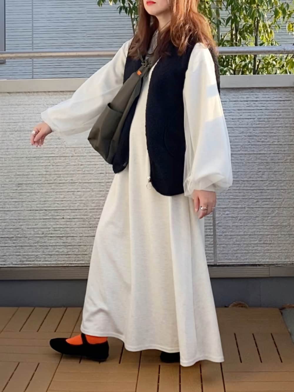 グレー系のワンピース、ブラック系のベスト、グリーン系のショルダーバッグを着用したレディースの春コーディネートの2枚目の写真