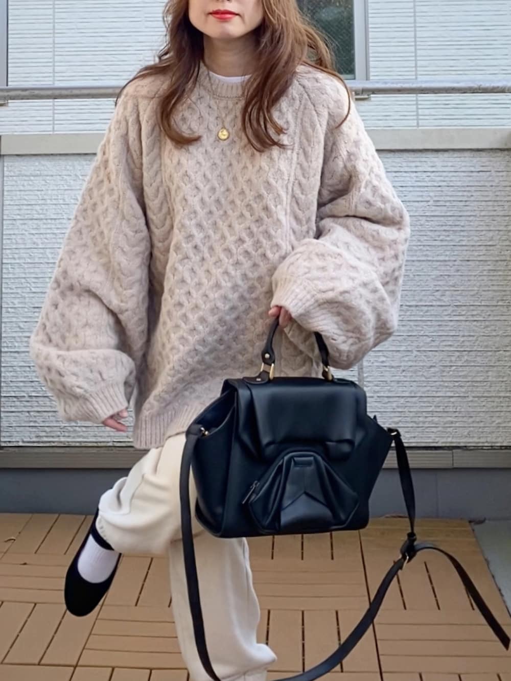 ベージュ系のニット/セーター、ホワイト系のパンツ、ブラック系のハンドバッグを着用したレディースの秋コーディネートの5枚目の写真