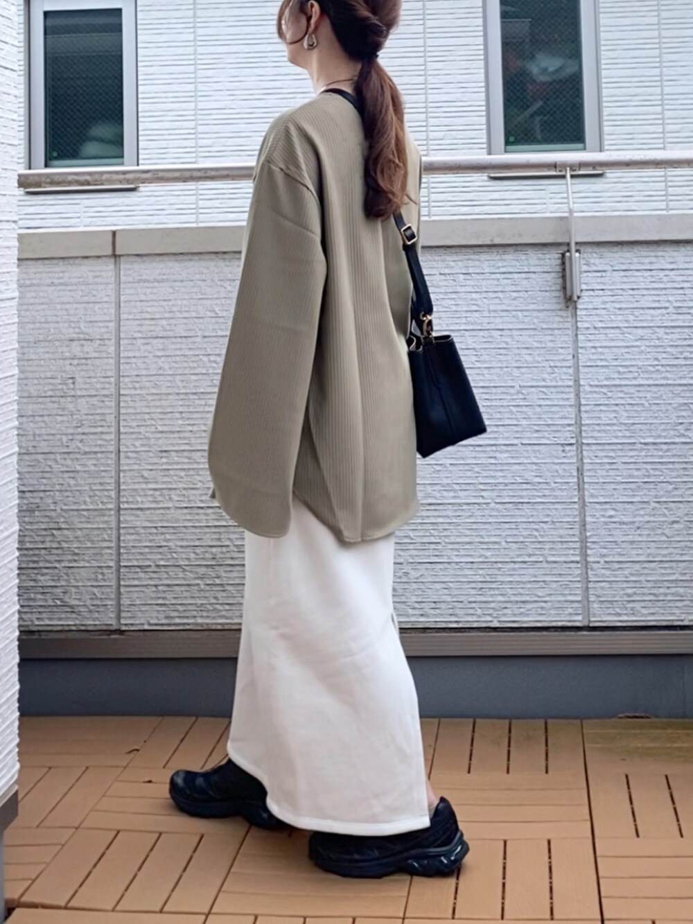 グリーン系のTシャツ/カットソー、ホワイト系のスカート、ブラック系のショルダーバッグを着用したレディースの秋コーディネートの3枚目の写真