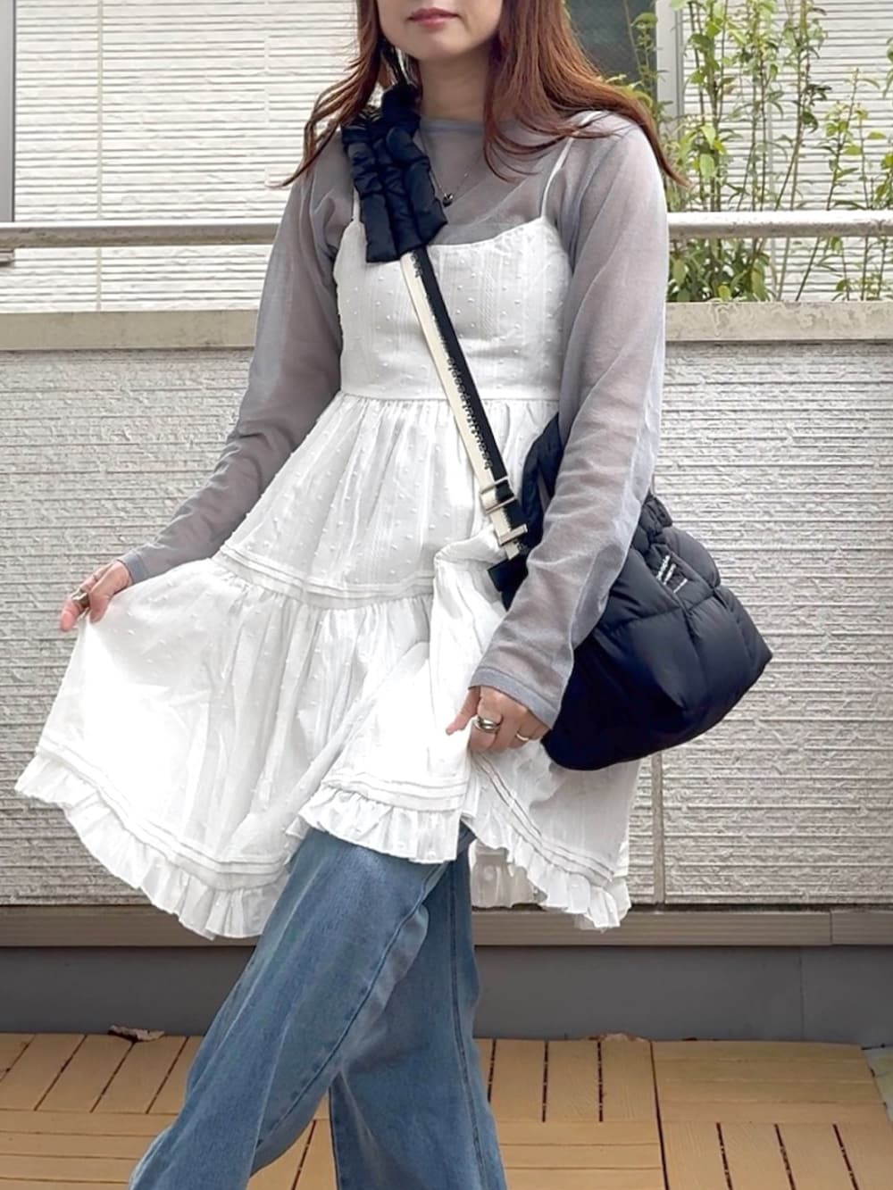 ホワイト系のワンピース、ブルー系のデニムパンツ、ブラック系のスニーカーを着用したレディースの春コーディネートの4枚目の写真