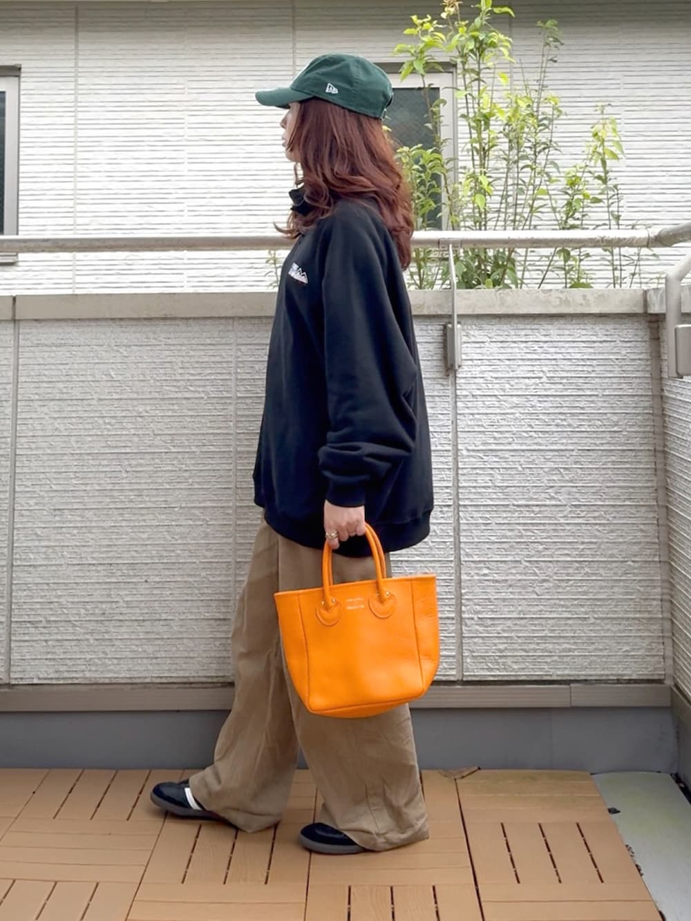 ブラック系のスウェット、オレンジ系のトートバッグ、ブラック系のスニーカーを着用したレディースの秋コーディネートの3枚目の写真