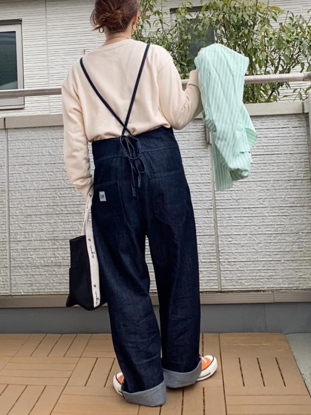 ブルー系のサロペット/オーバーオール、ホワイト系のスウェット、グリーン系のシャツ/ブラウスを着用したレディースの春コーディネートの2枚目の写真