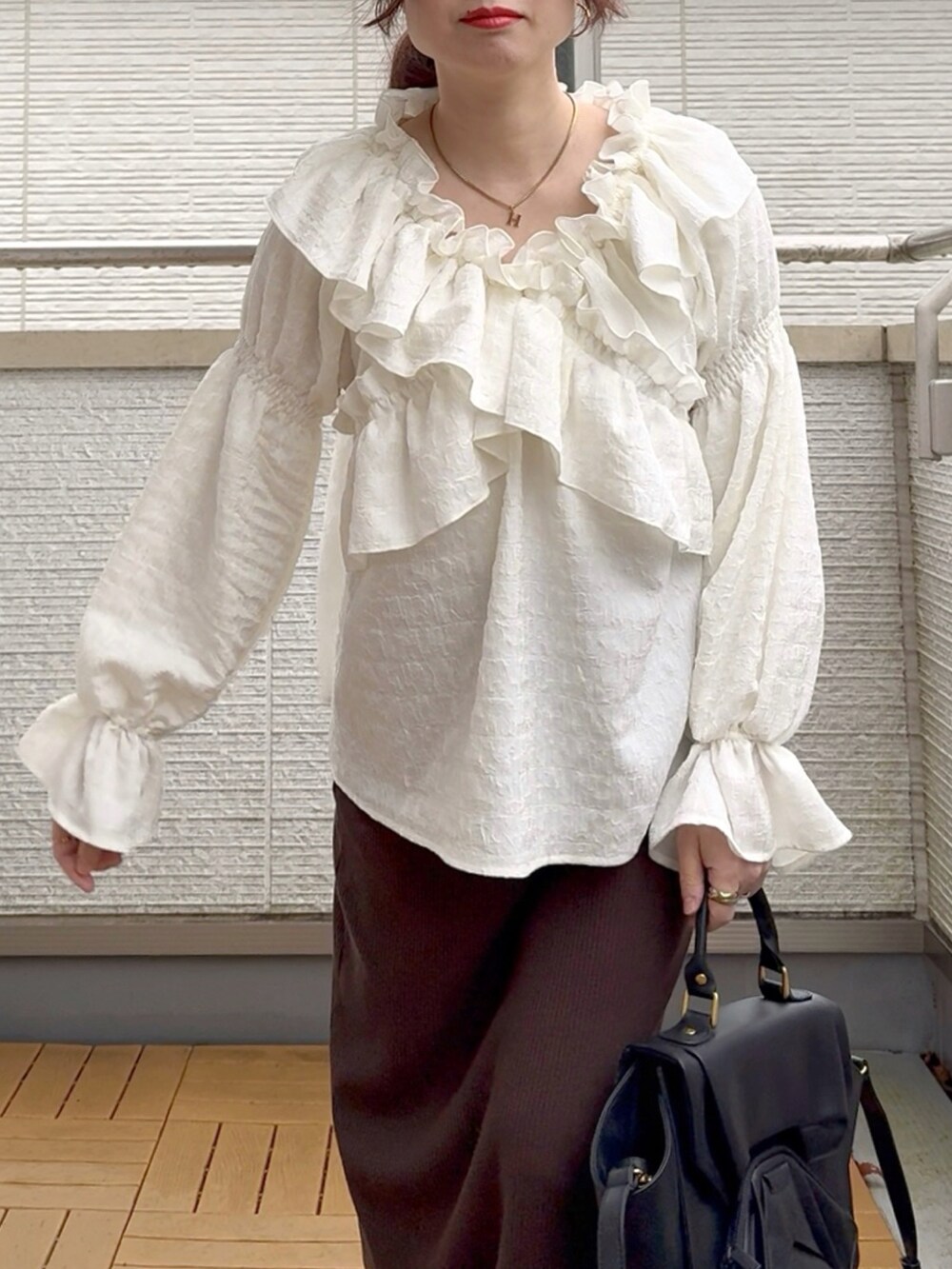 ホワイト系のシャツ/ブラウス、ブラウン系のスカート、ブラック系のハンドバッグを着用したレディースの春コーディネートの4枚目の写真