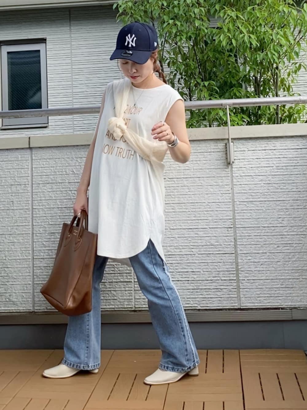 ホワイト系のタンクトップ、ブルー系のデニムパンツ、ブラウン系のトートバッグを着用したレディースの夏コーディネートの2枚目の写真