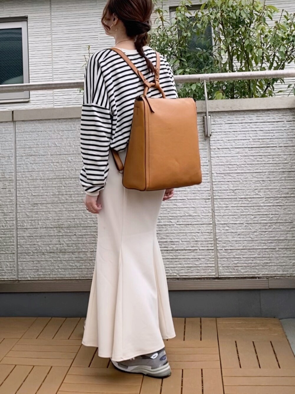 ブラック系のTシャツ/カットソー、ホワイト系のスカート、イエロー系のバックパック/リュックを着用したレディースの春コーディネートの2枚目の写真