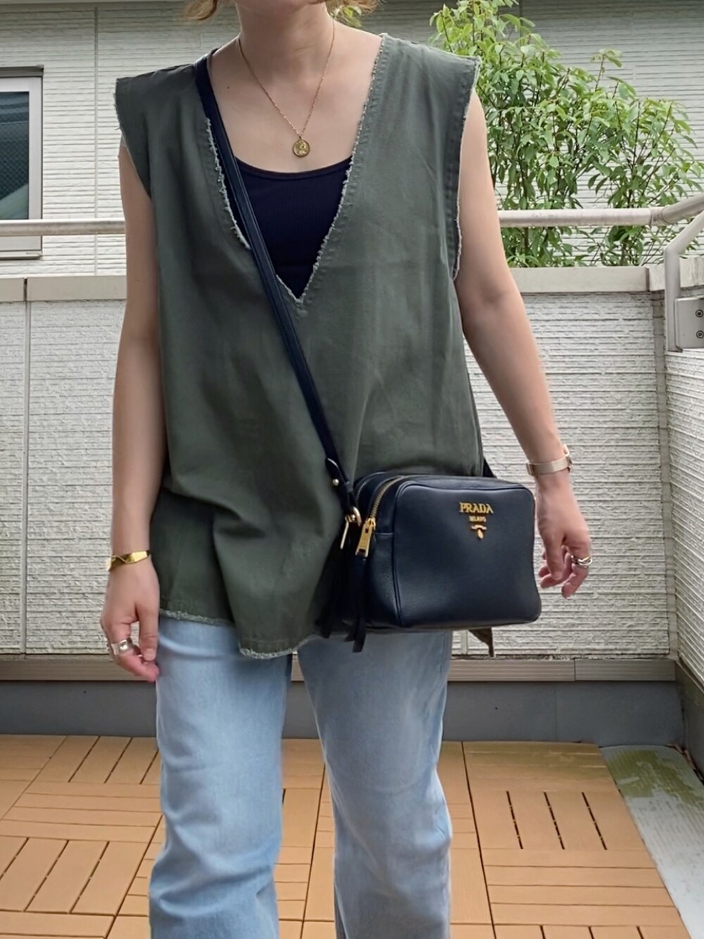 グリーン系のベスト、ブルー系のデニムパンツ、ブラック系のサンダルを着用したレディースの夏コーディネートの2枚目の写真
