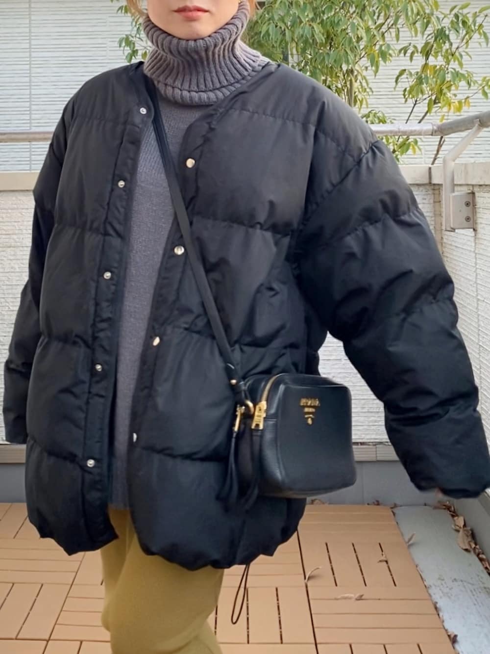 ブラック系のダウンジャケット/コート、グレー系のニット/セーター、グリーン系のスカートを着用したレディースの冬コーディネートの4枚目の写真