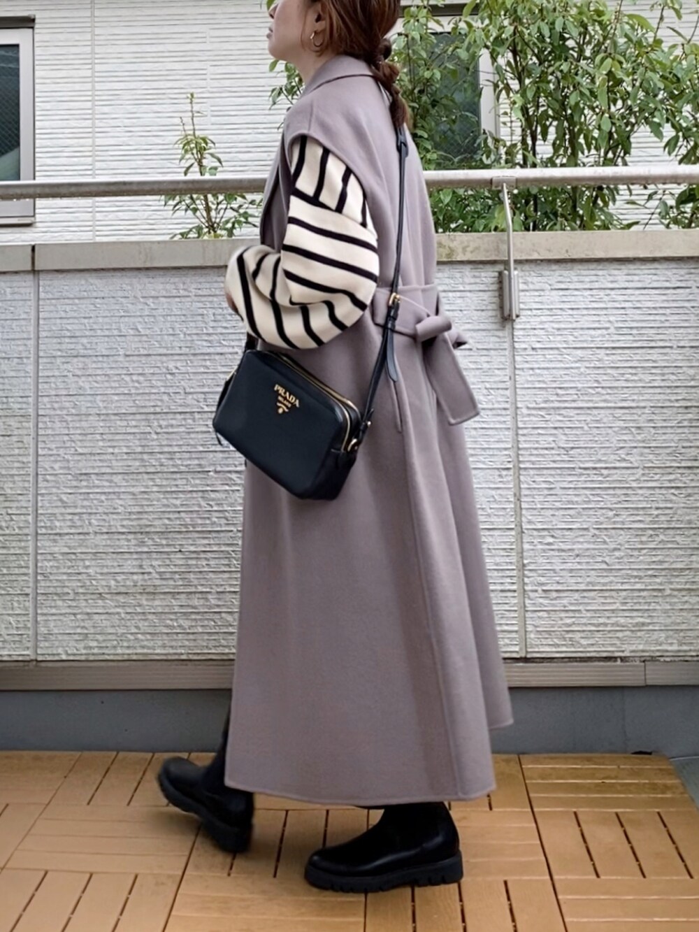 ブラウン系のチェスターコート、ホワイト系のニット/セーター、ブラック系のスカートを着用したレディースの秋コーディネートの2枚目の写真