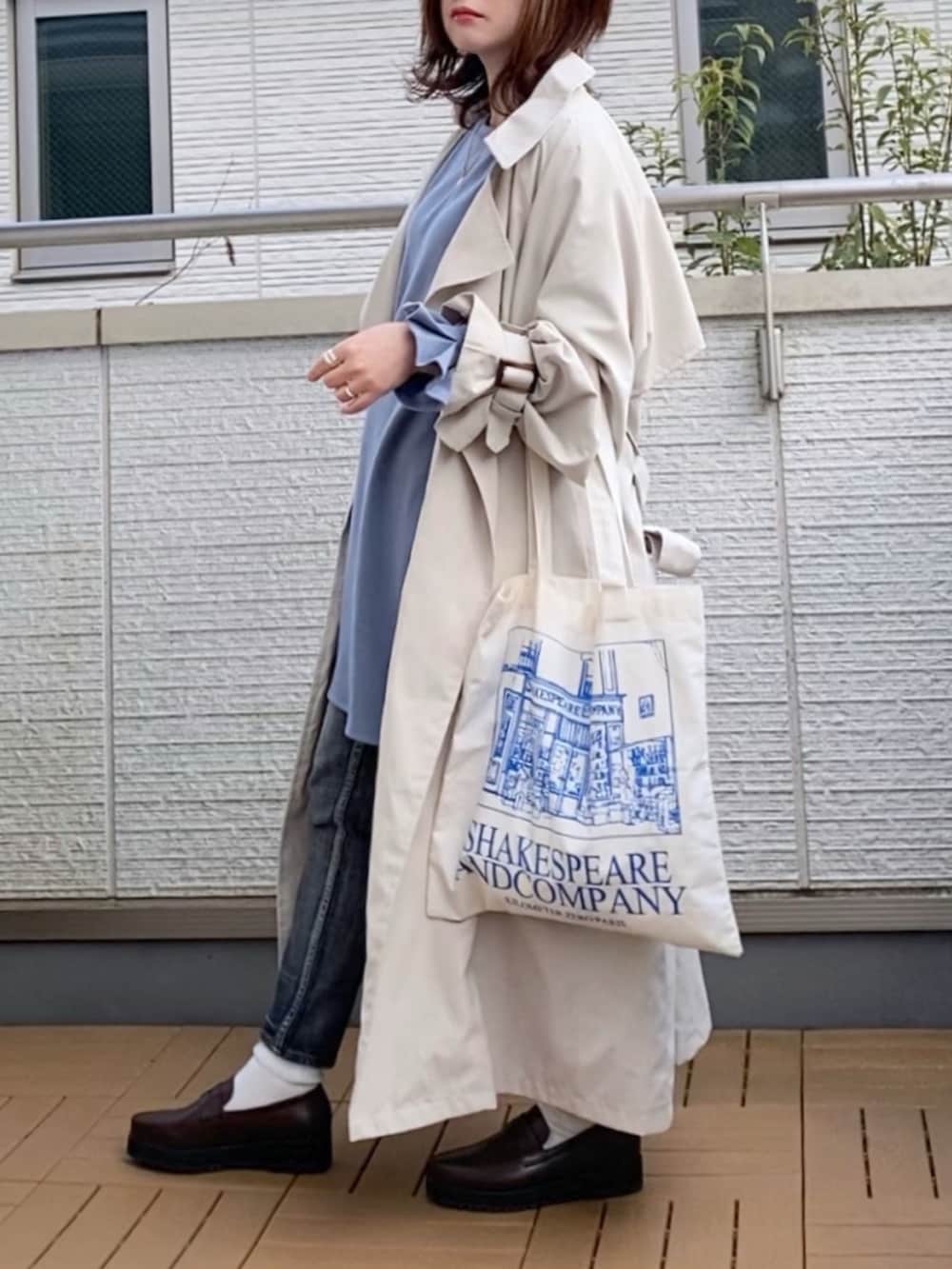 ベージュ系のトレンチコート、ブルー系のTシャツ/カットソー、ブラック系のデニムパンツを着用したレディースの春コーディネートの2枚目の写真