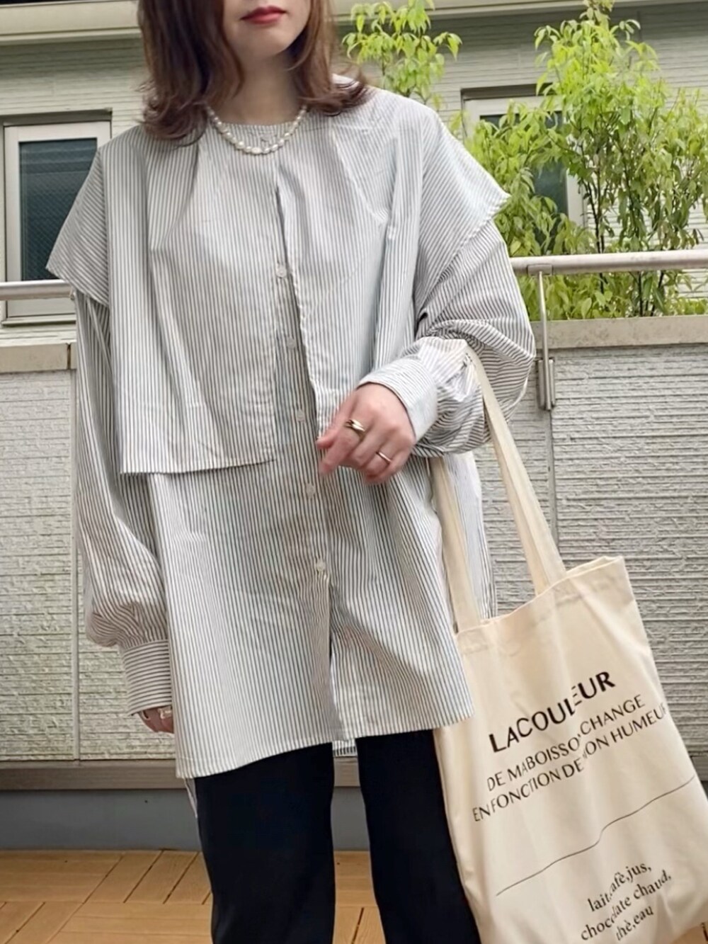 ブラック系のシャツ/ブラウス、ブラック系のスラックス、ホワイト系のトートバッグを着用したレディースの春コーディネートの2枚目の写真