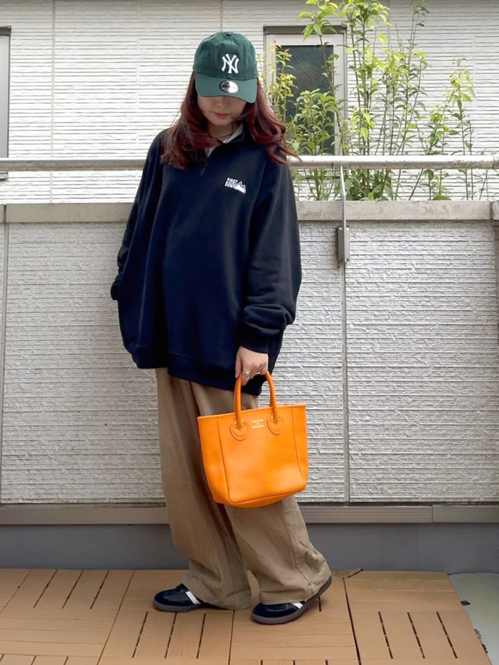 ブラック系のスウェット、オレンジ系のトートバッグ、ブラック系のスニーカーを着用したレディースの秋コーディネートの2枚目の写真