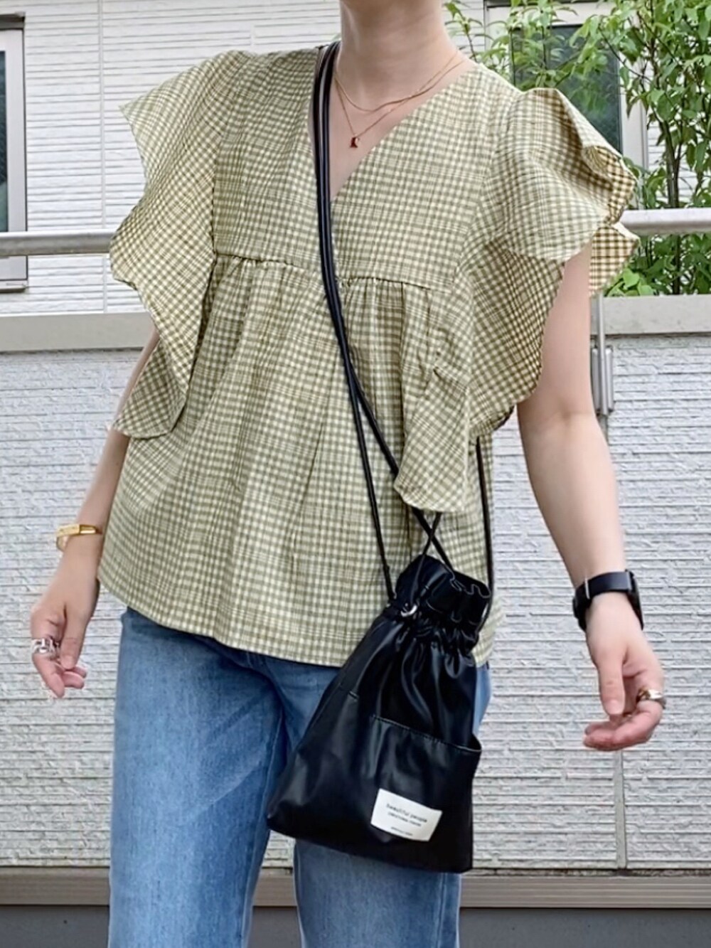 ベージュ系のシャツ/ブラウス、ブルー系のデニムパンツ、ブラック系のショルダーバッグを着用したレディースの夏コーディネートの2枚目の写真