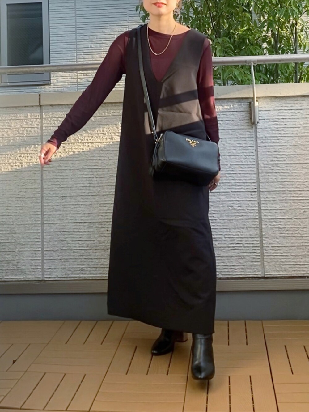 ブラウン系のTシャツ/カットソー、ブラック系のジャンパースカート、ブラック系のブーツを着用したレディースの秋コーディネートの2枚目の写真