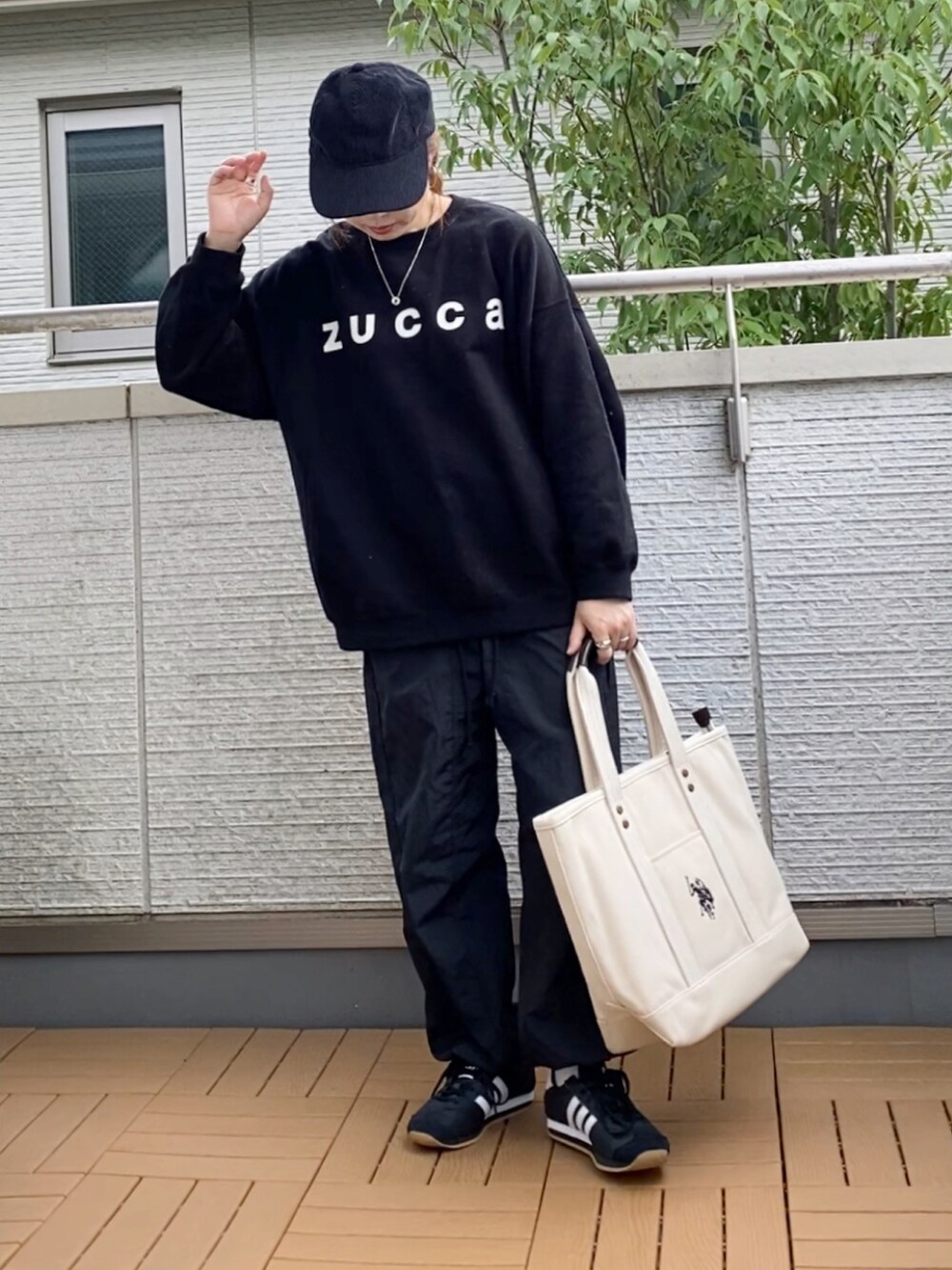 ブラック系のスウェット、ブラック系のカーゴパンツ、ホワイト系のトートバッグを着用したレディースの秋コーディネートの2枚目の写真