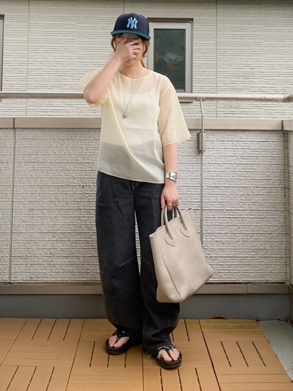 ホワイト系のシャツ/ブラウス、ブラック系のデニムパンツ、ベージュ系のトートバッグを着用したレディースの夏コーディネートの2枚目の写真