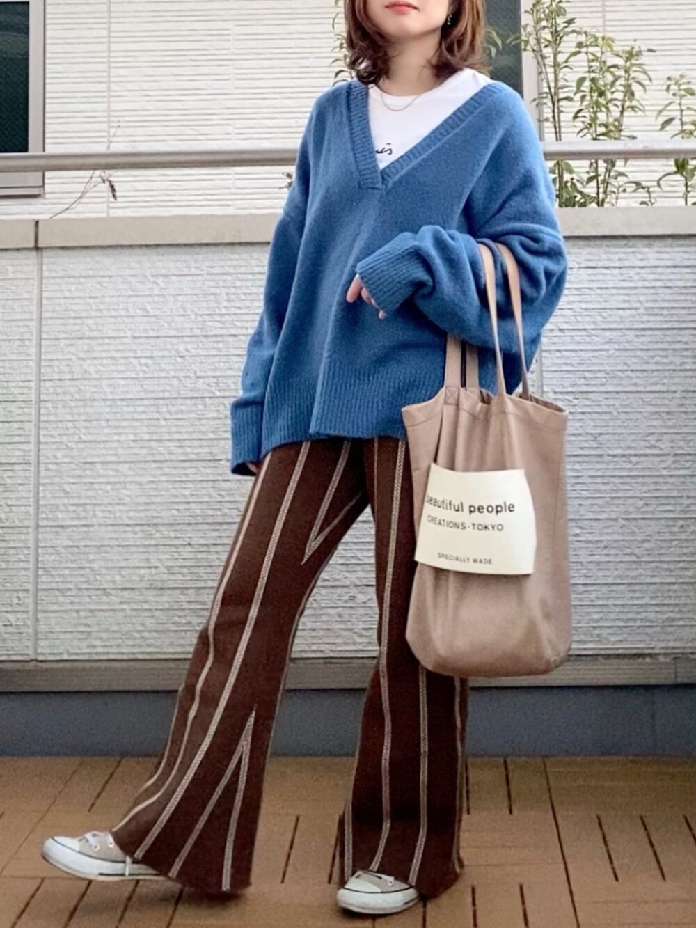 ブルー系のニット/セーター、ブラウン系のスウェットパンツ、ベージュ系のトートバッグを着用したレディースの冬コーディネートの2枚目の写真