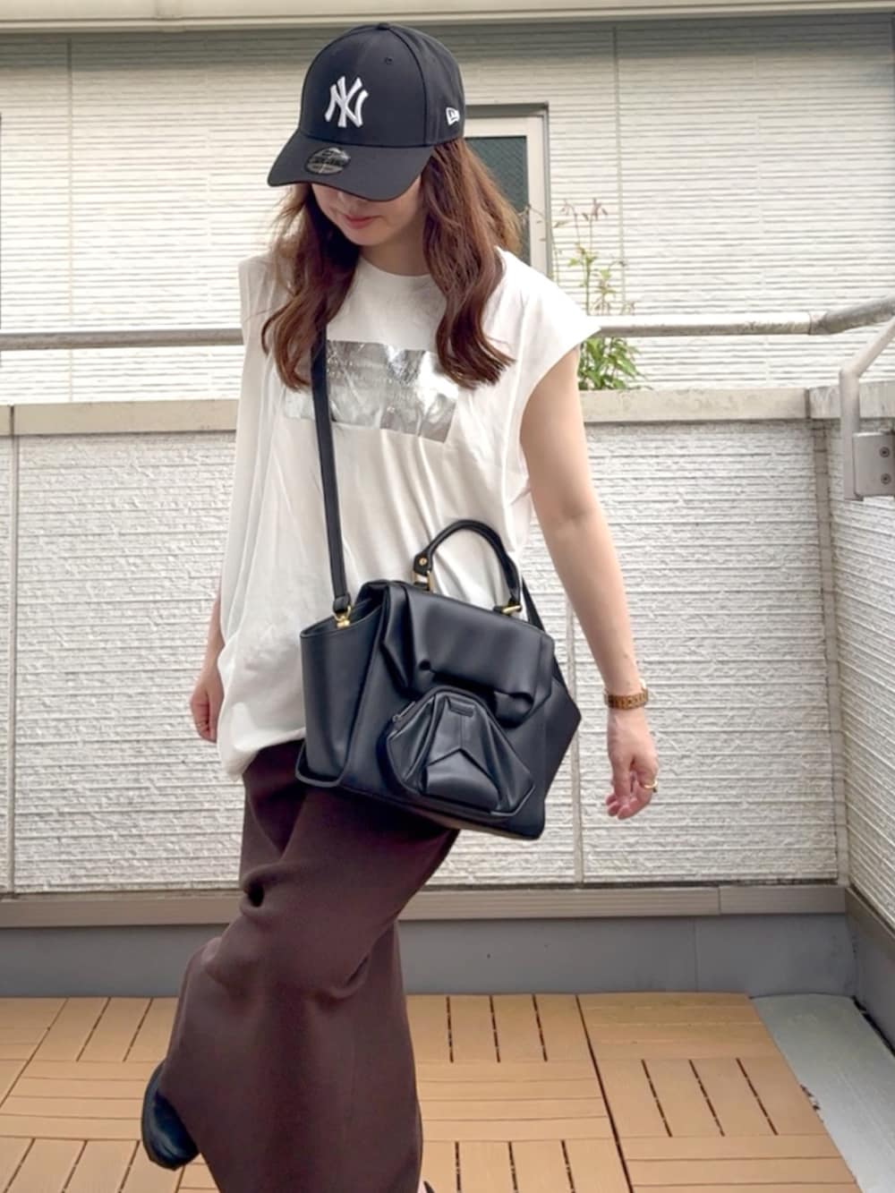 ホワイト系のTシャツ/カットソー、ブラウン系のスカート、ブラック系のハンドバッグを着用したレディースの夏コーディネートの4枚目の写真
