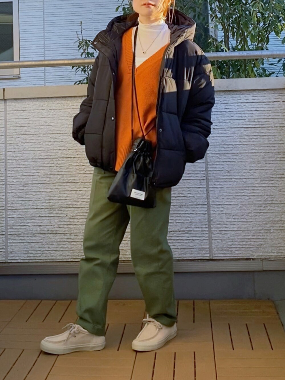 オレンジ系のニット/セーター、グリーン系のその他パンツ、ブラック系のダウンジャケット/コートを着用したレディースの冬コーディネートの3枚目の写真