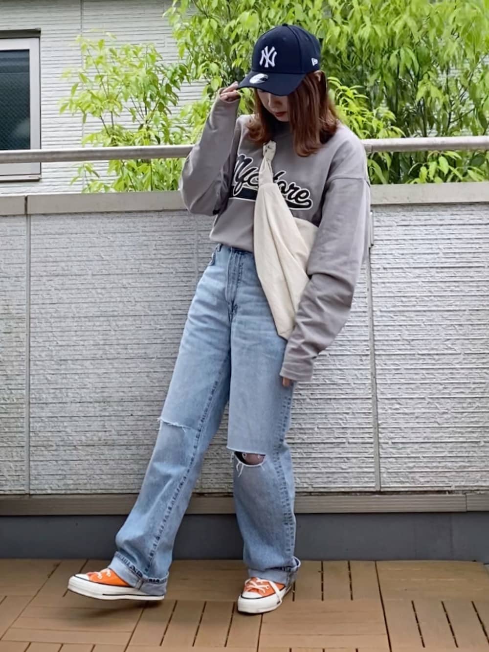 グレー系のTシャツ/カットソー、ブルー系のデニムパンツ、ホワイト系のショルダーバッグを着用したレディースの春コーディネートの2枚目の写真