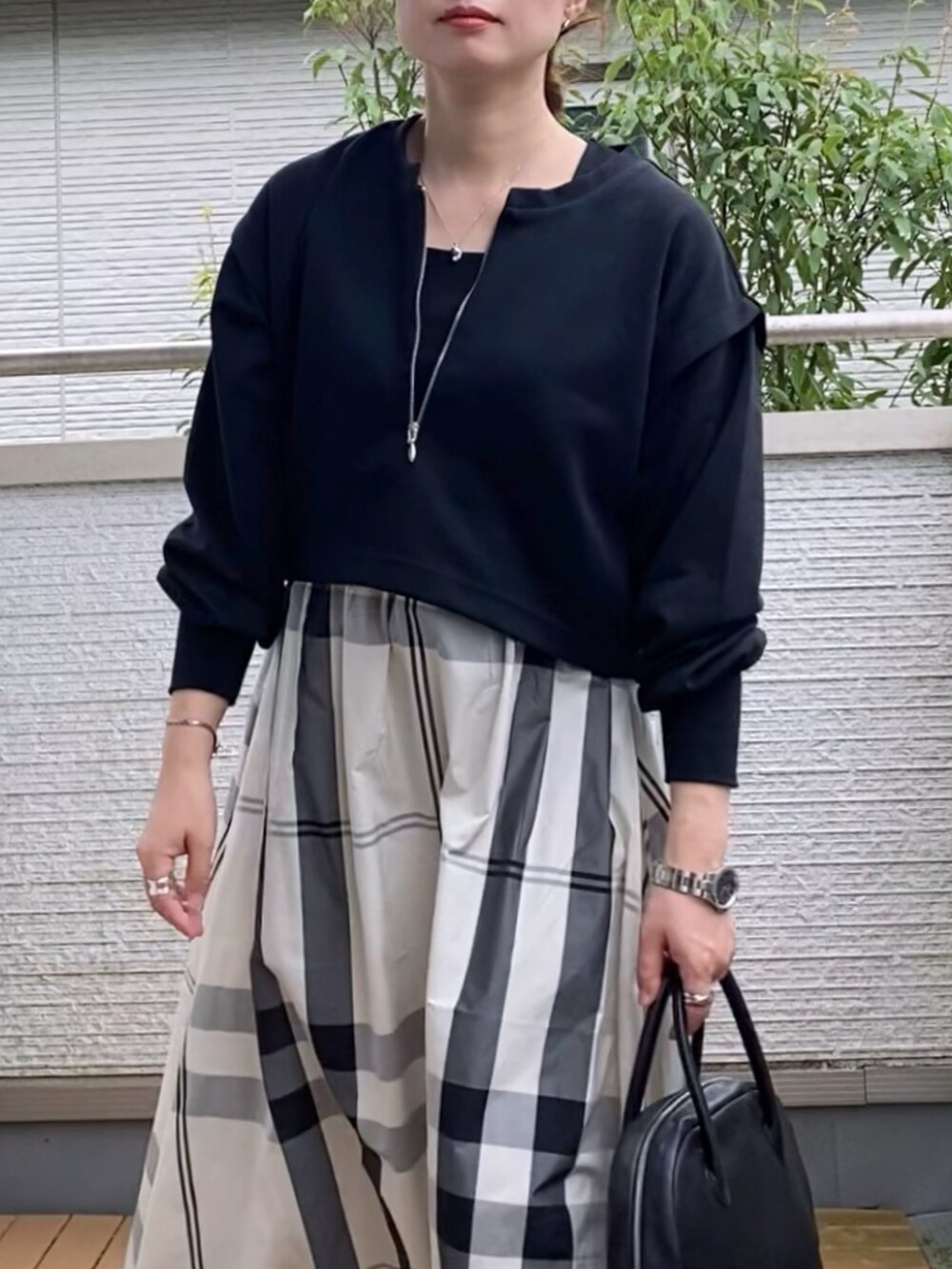 ブラック系のワンピース、ブラック系のショルダーバッグ、ホワイト系のスニーカーを着用したレディースの秋コーディネートの2枚目の写真