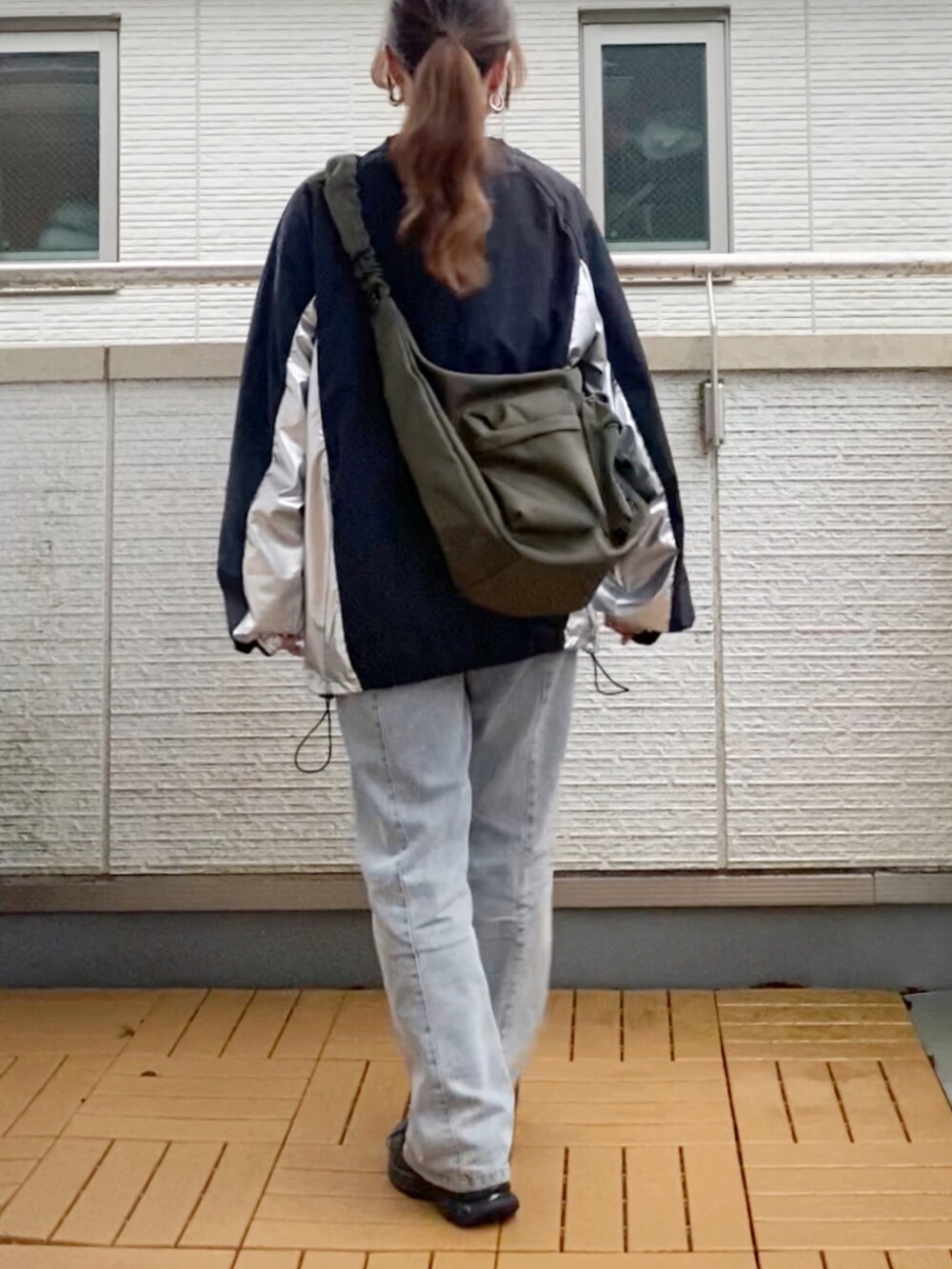 ブラック系のトップス、ブルー系のデニムパンツ、グリーン系のショルダーバッグを着用したレディースの秋コーディネートの4枚目の写真