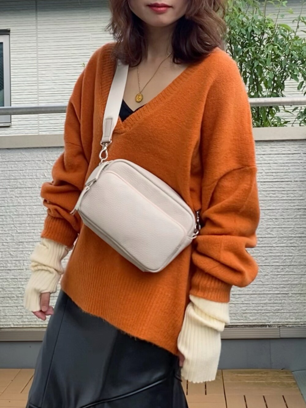 オレンジ系のニット/セーター、ブラック系のスカート、ブラウン系のショルダーバッグを着用したレディースの秋コーディネートの2枚目の写真