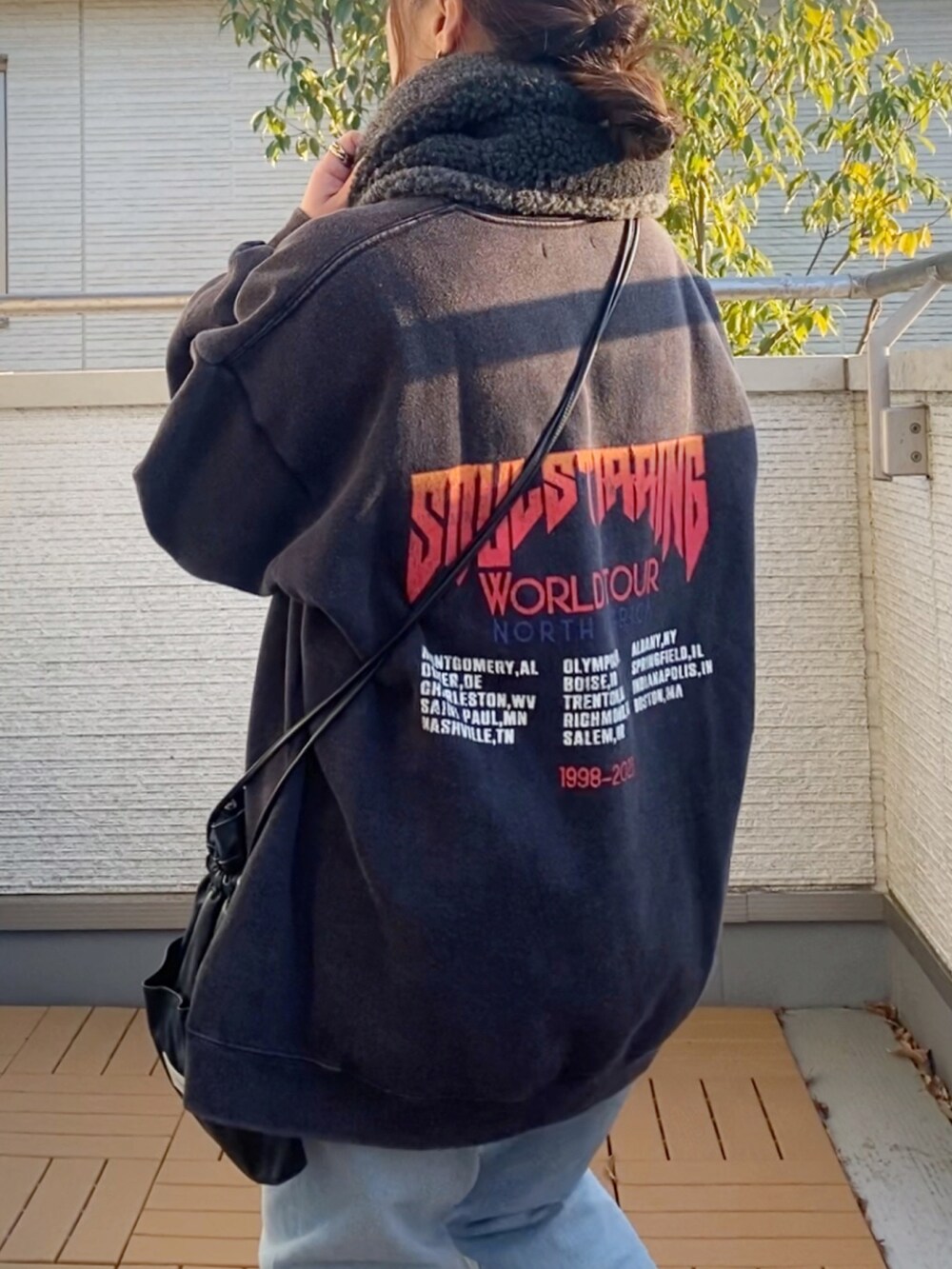 グレー系のスウェット、ブルー系のデニムパンツ、ブラック系のショルダーバッグを着用したレディースの冬コーディネートの3枚目の写真