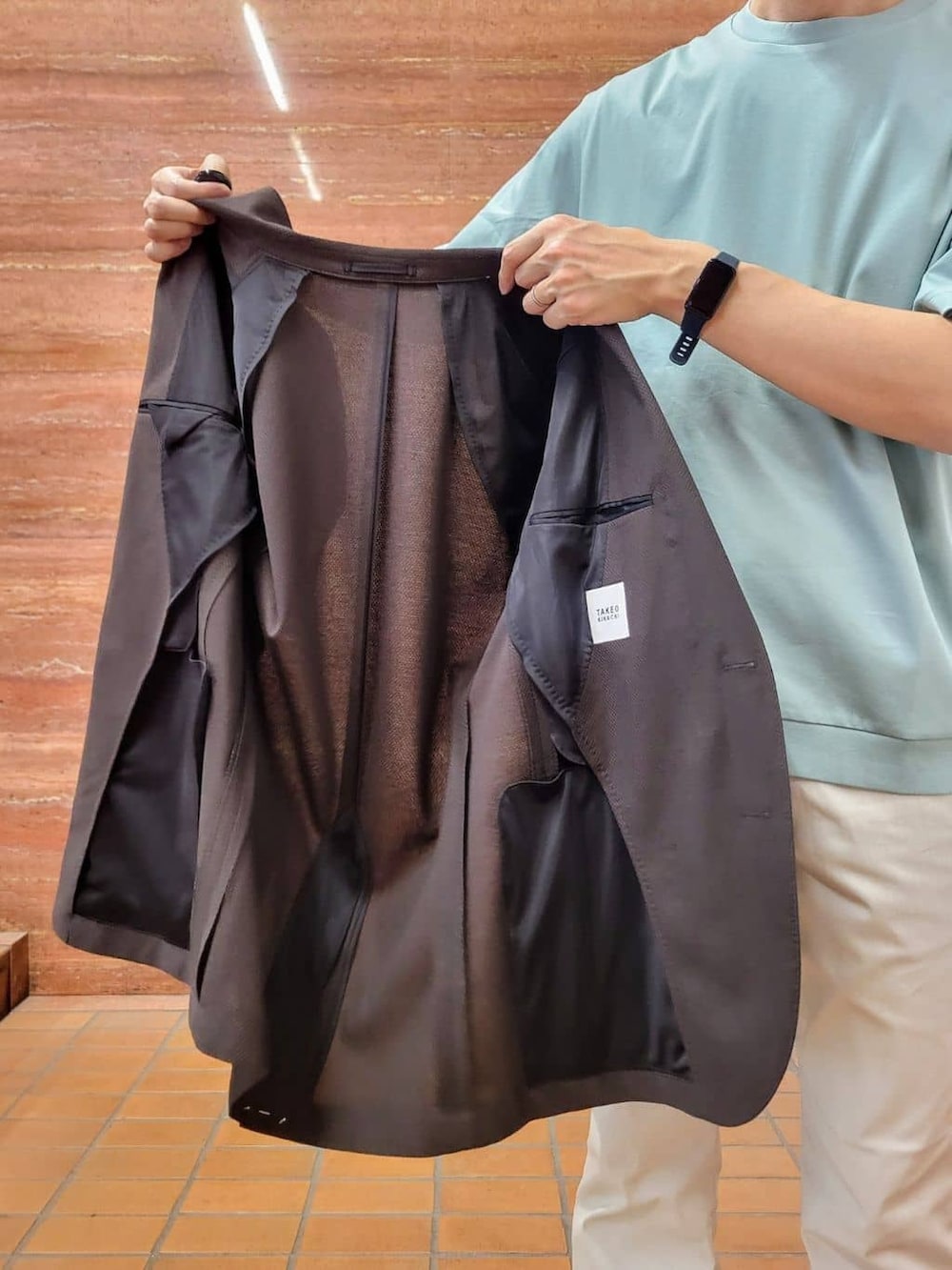 グリーン系のTシャツ/カットソー、ベージュ系のスラックス、ホワイト系のスニーカーを着用したメンズの春コーディネートの10枚目の写真