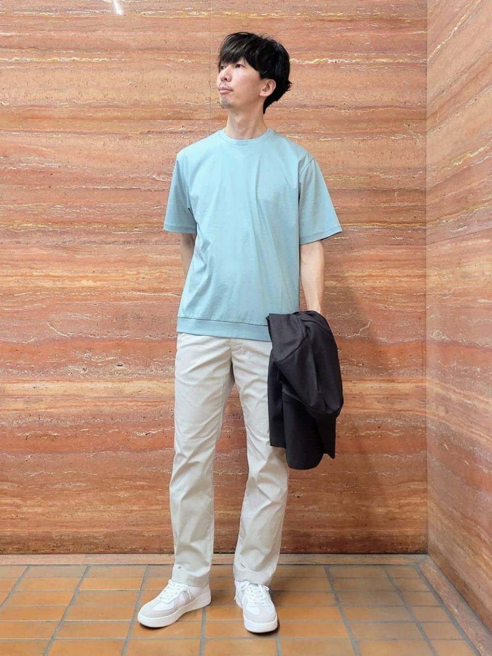 グリーン系のTシャツ/カットソー、ベージュ系のスラックス、ホワイト系のスニーカーを着用したメンズの春コーディネートの7枚目の写真