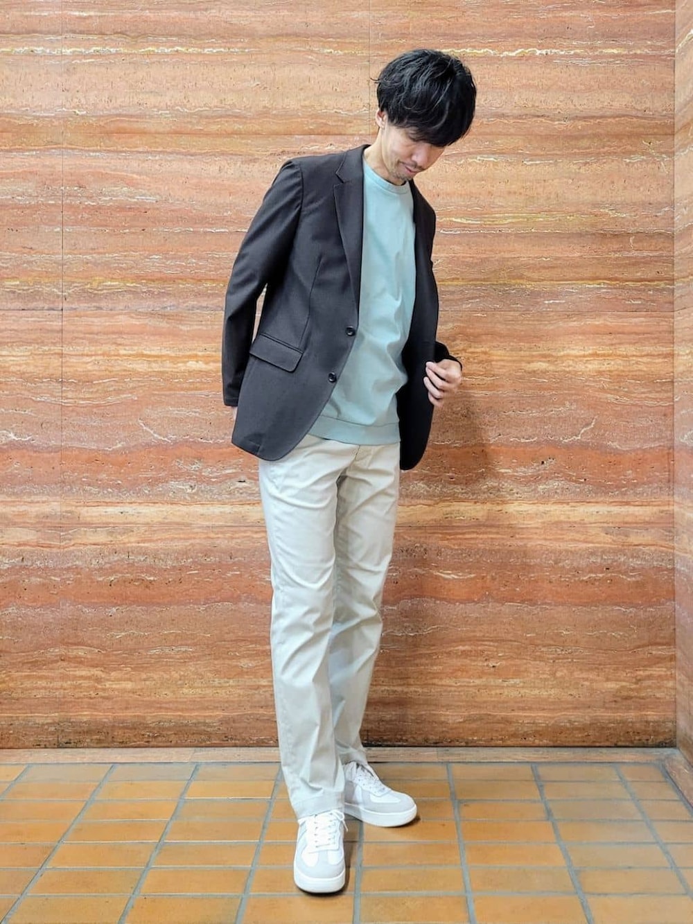グリーン系のTシャツ/カットソー、ベージュ系のスラックス、ホワイト系のスニーカーを着用したメンズの春コーディネートの6枚目の写真