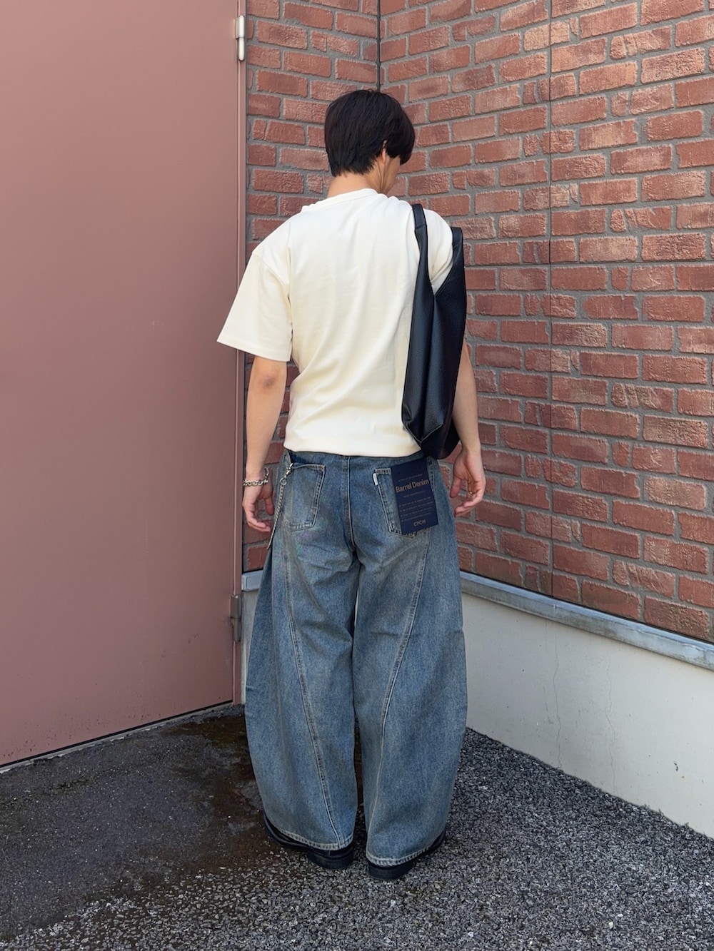 ホワイト系のTシャツ/カットソー、ブルー系のデニムパンツ、ブラック系のトートバッグを着用したメンズの春コーディネートの2枚目の写真