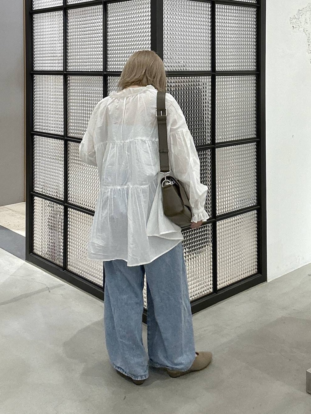 ブラウン系のショルダーバッグ、ブルー系のデニムパンツ、ベージュ系のパンプスを着用したレディースの春コーディネートの3枚目の写真