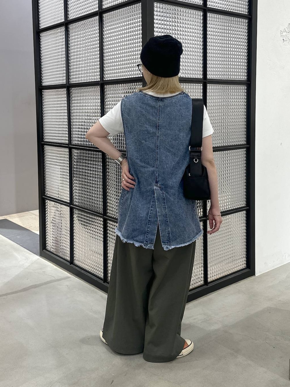 ブラック系のショルダーバッグ、ブルー系のベスト、グリーン系のその他パンツを着用したレディースの夏コーディネートの4枚目の写真