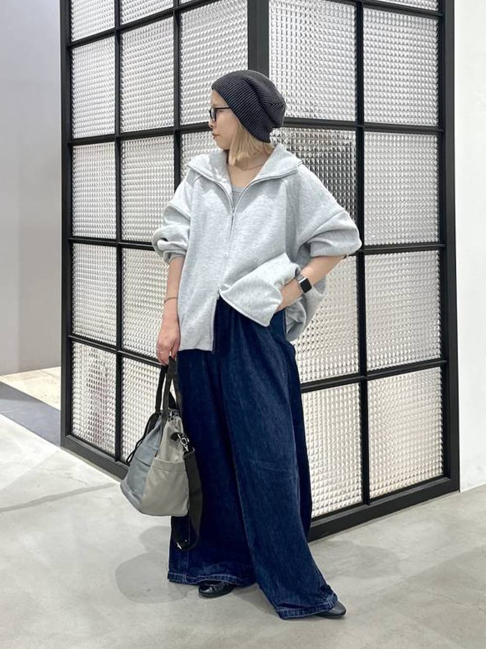 グリーン系のショルダーバッグ、ブルー系のデニムパンツ、ブラック系のニットキャップ/ビーニーを着用したレディースの秋コーディネートの2枚目の写真